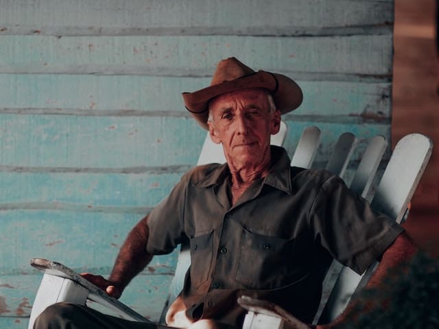 relaxed athletic older man with cowboy hat sitting on his porch